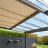 Terrassenüberdachung mit beige-farbenem Sonnenschutz und Glasdach bei blauem Himmel.