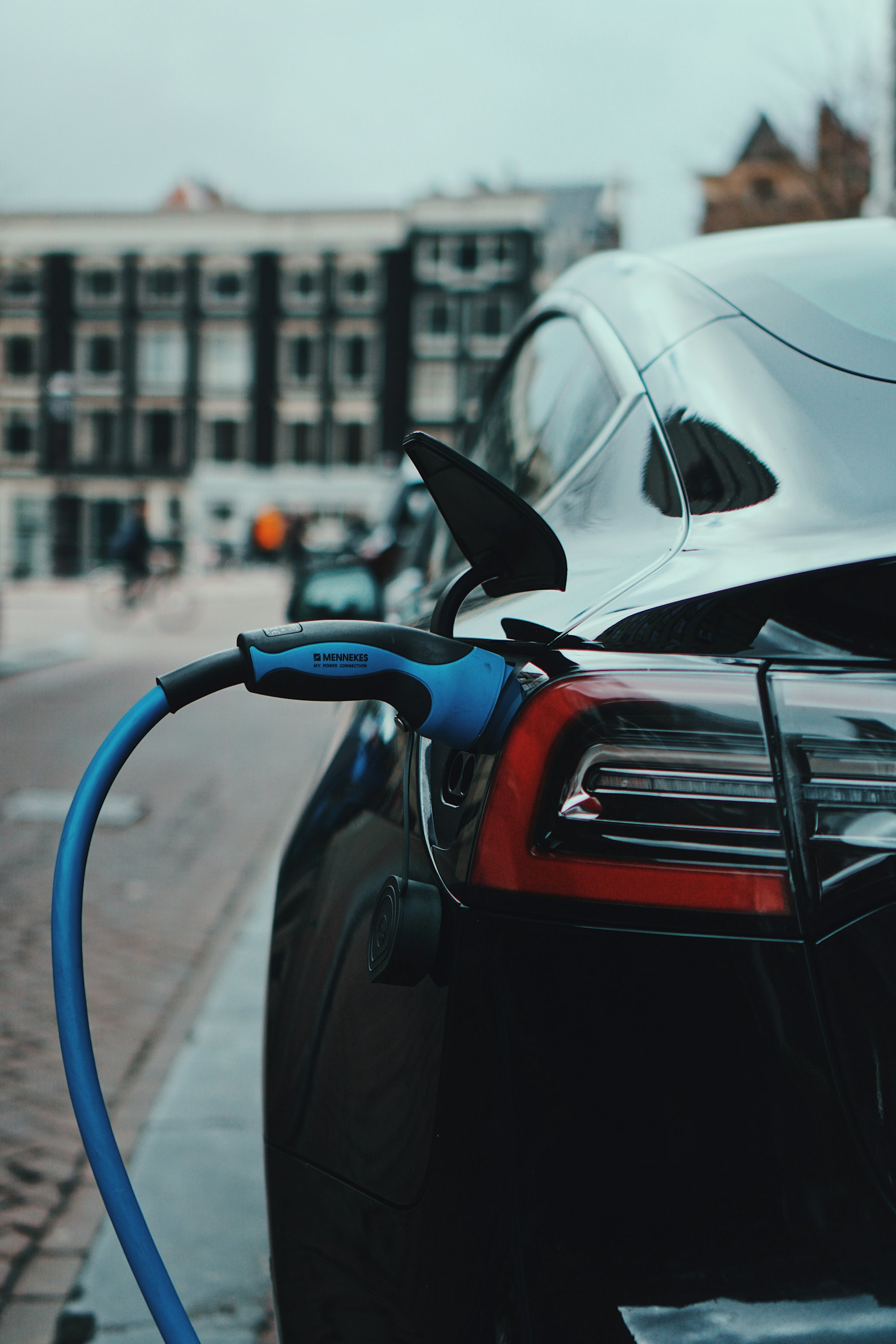 Pedestal-mounted dual EV charging stations in a commercial parking lot protected by bollards