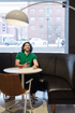 James Lanigan in a green polo shirt holding a phone, sitting at a table with a red mug in a cafe.