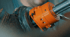 Eine orangefarbene, zylindrische Maschine, die in ein dunkles Metallrohr eingesetzt ist.