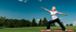 Woman practices yoga on a mat in a park, promoting flexibility and pain relief.