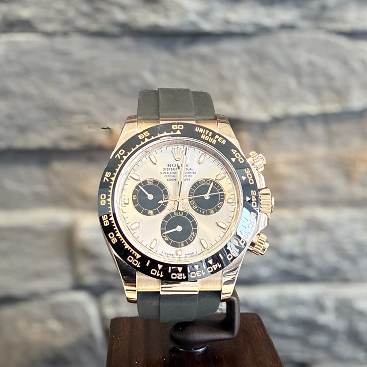 Goldene Rolex Daytona Uhr mit schwarzem Zifferblatt und Chronographen auf schwarzem Ständer.