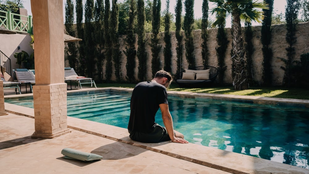 Mann sitzt am Pool der Unterkunft