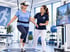 Senioren beim VR-Gleichgewichtstraining mit Therapeutin, gesichert durch Gurtsystem auf einer Sensorplattform.