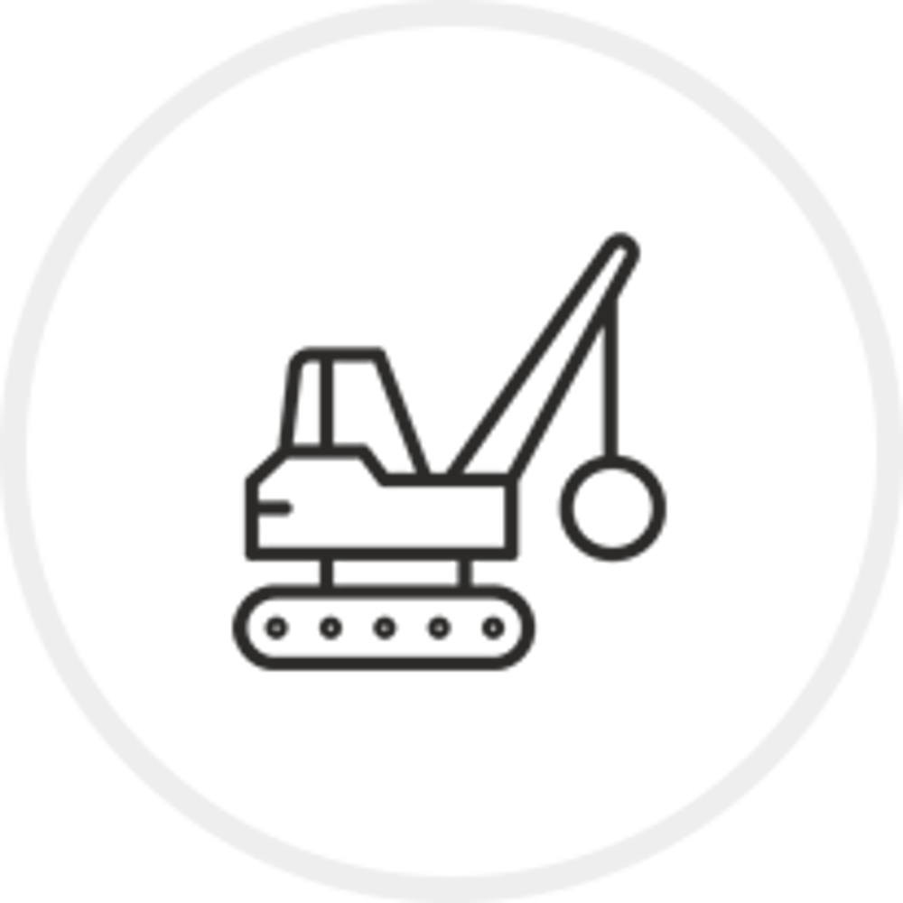 Ein Abrissbagger mit Abrissbirne auf einem grünen Kreis.