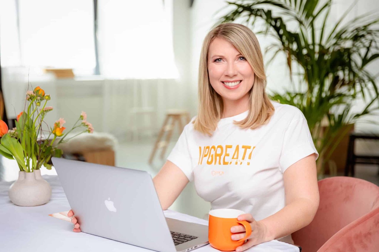 Susanne Kettler lächelnd am Laptop mit Kaffeetasse