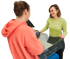 Eine lächelnde Verkäuferin reicht einem Kunden an der Kasse ein Kartenlesegerät für die kontaktlose Zahlung.