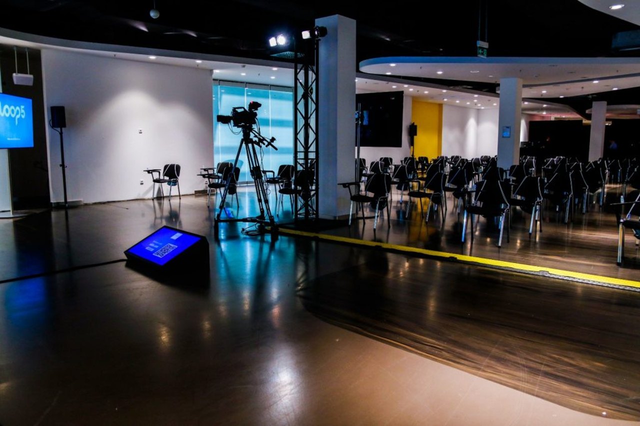 Kamera auf Stativ vor bestuhltem Saal während eines hybriden Events