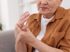 An elderly woman in brown suffering from joint and arthritis pain.