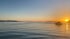 Sonnenuntergang über dem Meer mit Bergen, einem Boot und einem Paddelbootfahrer in Drage Kroatien.