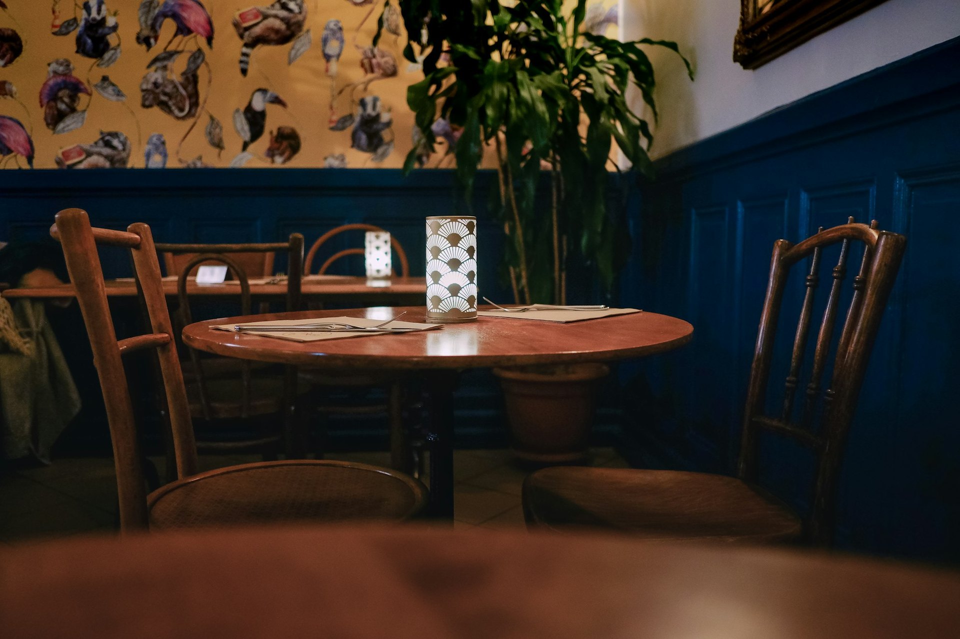Ein runder Tisch mit zwei leeren Stühlen in einem gedämpft beleuchteten Restaurant