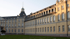 Das Karlsruher Schloss, ein großes, cremefarbenes Barockgebäude mit einem Turm, einem Dach und vielen Fenstern.