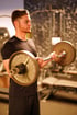 Zu sehen ist ein Mann beim Bizeps-Training mit der Langhantel – konzentriert und kraftvoll.