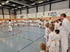 Karate-Schüler und Keigo Shimizu Sensei in weißen Anzügen stehen in einer Turnhalle im Kreis.