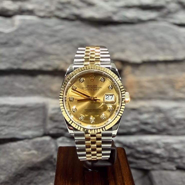Goldene und silberne Rolex Oyster Perpetual Datejust Uhr mit Diamanten auf Holzständer.