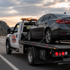 Towing Deltona long-distance towing service transporting a secured sedan on a flatbed truck along the highway at sunset