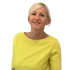 Lächelnde Frau mit kurzem blondem Haar und gelbem Oberteil.