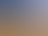 Weite Wüstenlandschaft mit sandigen Dünen, feinen Wellenmustern und trockenem Gras unter einem klaren blauen Himmel.