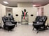 Four black leather medical traction chairs arranged in an integrative medicine therapy room with a spinal health wall logo.