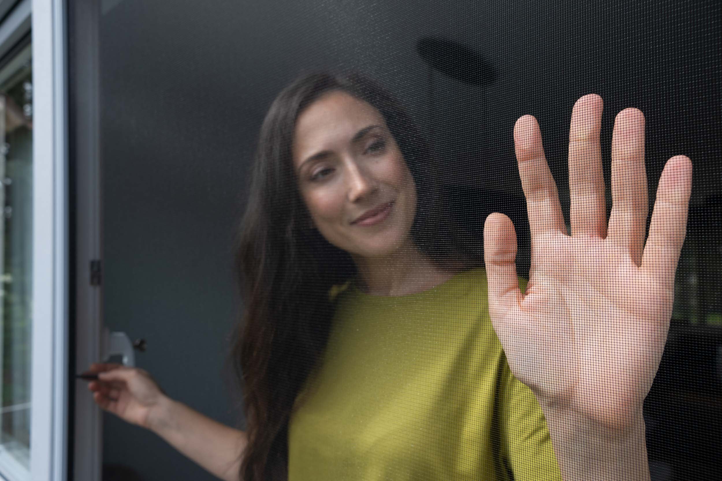 Hand an einem Insektenschutzgewebe in einer Tür, das Gewebe bleibt fast unsichtbar