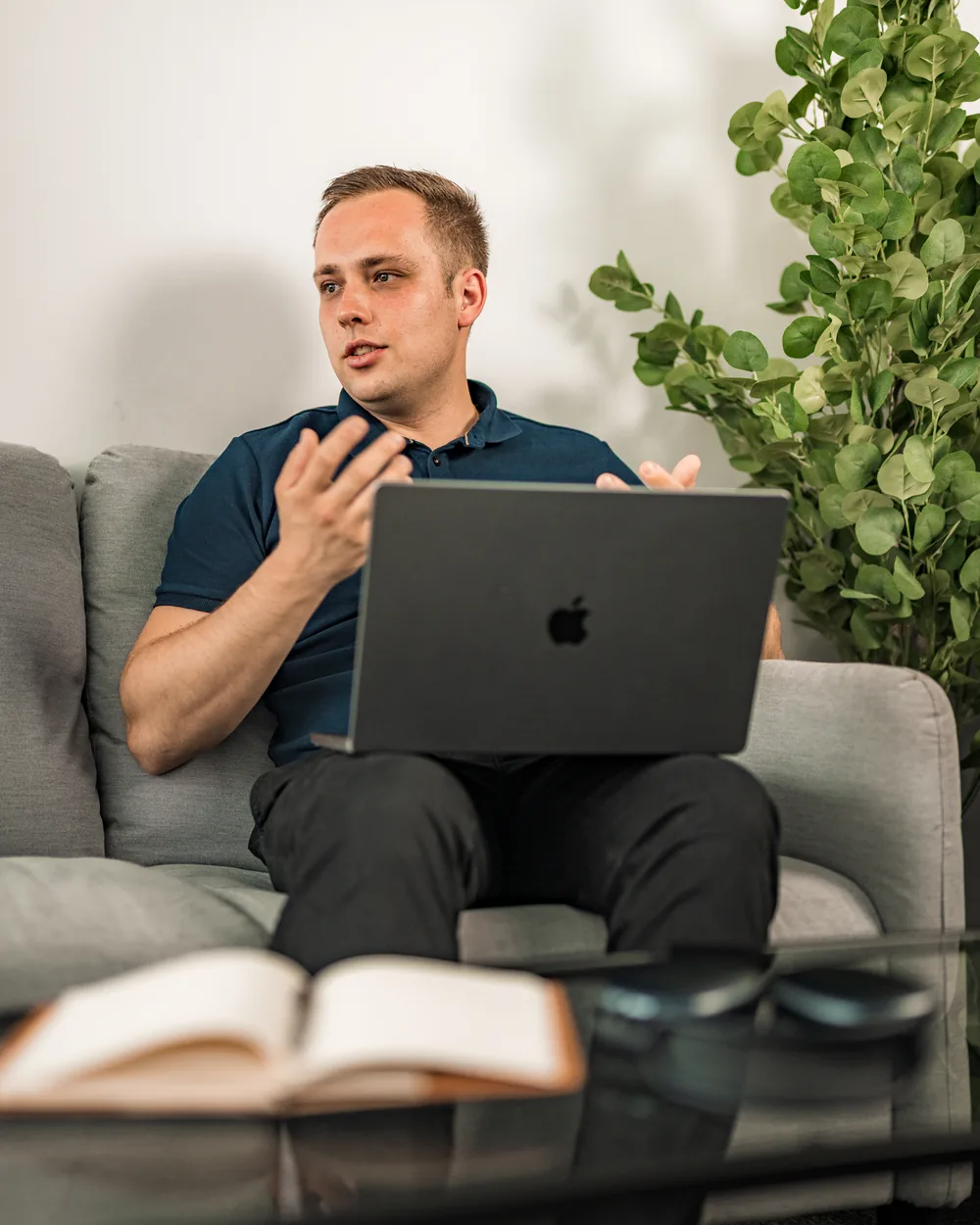 Alexander Pfeifer sitzt entspannt mit dem Laptop auf dem Sofa und erklärt etwas