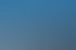 Zwei Arbeiter tragen ein Solarmodul über ein Flachdach mit installierten Solaranlagen unter blauem Himmel.