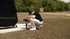Ein Kameramann hockt im Freien und stellt eine Kamera auf einem Gimbal-Stabilisator ein.