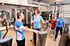 Frau trainiert an einem Stepper mit einem Trainer im Fitnessstudio.