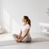 She sits on a yoga mat in a butterfly stretch, facing bladder leakage.