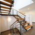 Moderne Holztreppe mit schwarzen Metallgeländern in einem hellen Eingangsbereich eines Hauses.