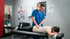 Chiropractor adjusts a patient lying face down on an examination table