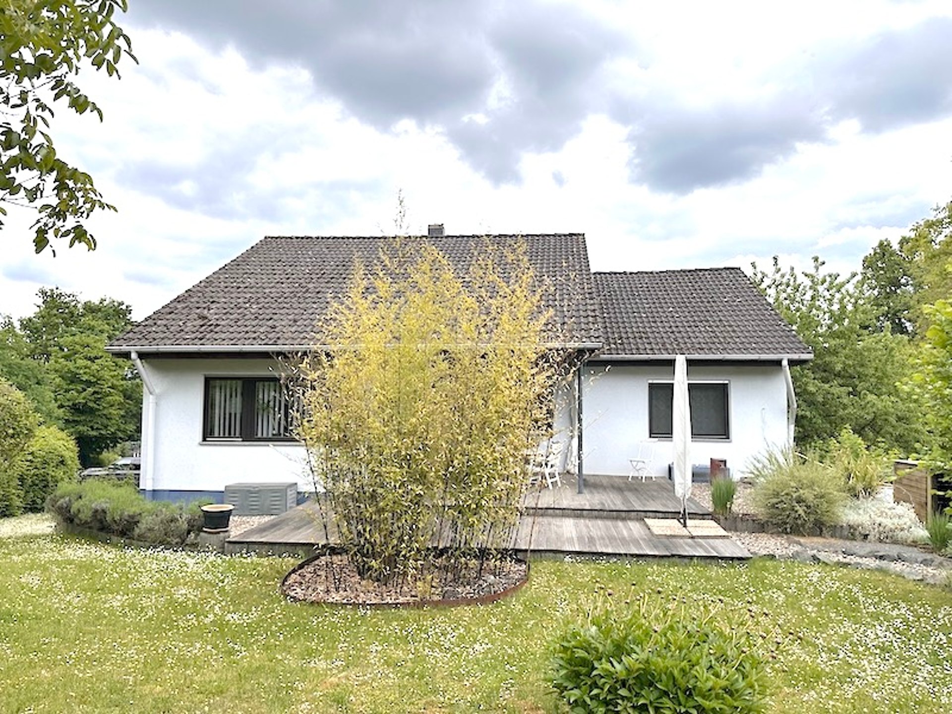 Freistehendes Einfamilienhaus mit weißer Fassade und gepflegtem Vorgarten bei Tageslicht