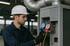 Techniker in weißem Helm und Handschuhen wartet Klimaanlage mit Manometern.