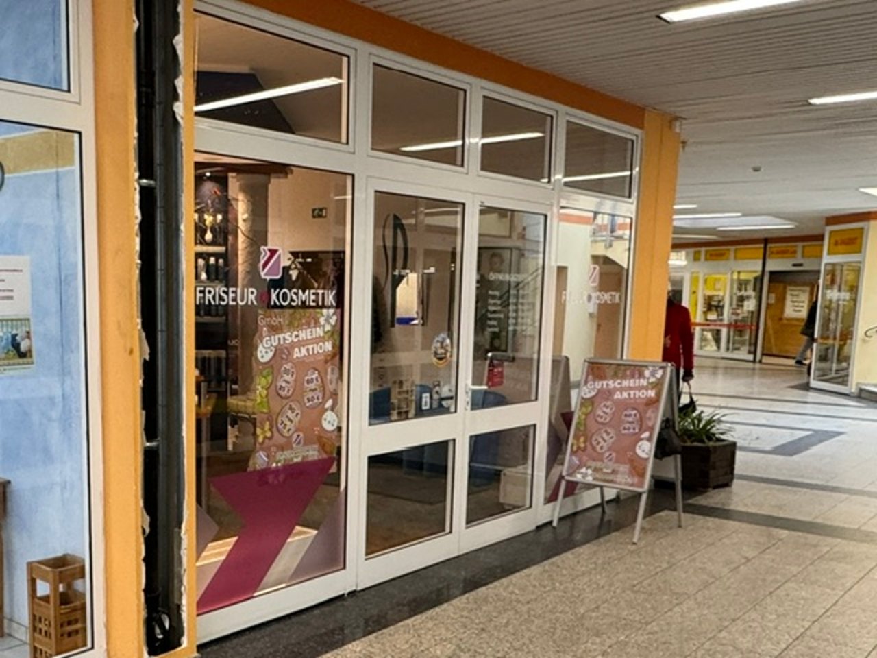 Blick in eine Einkaufspassage mit Schaufenster eines Friseur- und Kosmetiksalons
