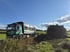 Ein MAN-LKW steht auf einem Feldweg neben einem großen Haufen Grünschnitt unter blauem Himmel.