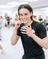 Phil - Boxtrainer BACKYARD Wien - Trainer in Boxing Stance lacht in die Kamera während das Boxtraining im Hintergrund läuft