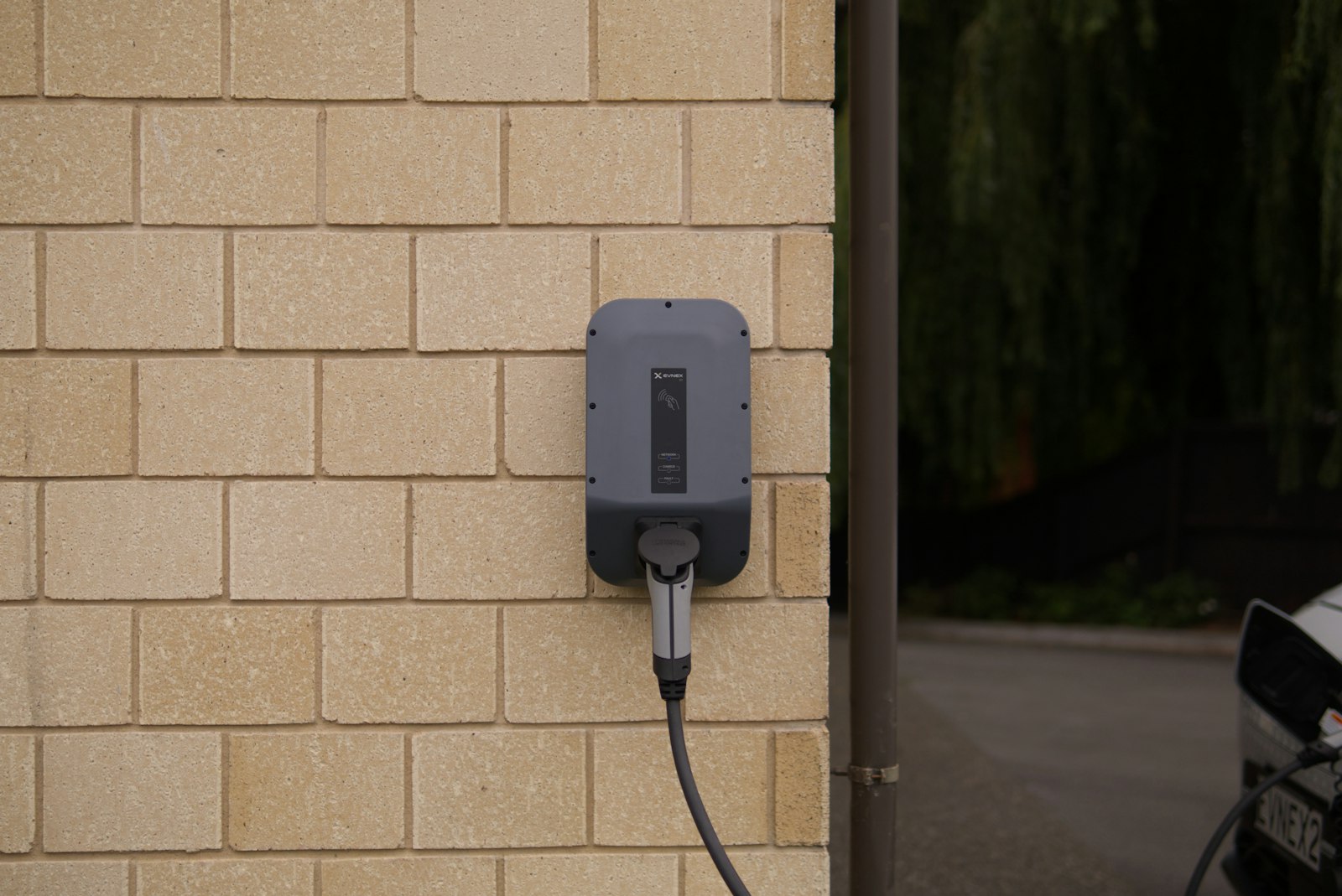 Black charging plug inserted into a wall-mounted electrical socket