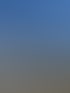 Drei Männer stehen auf einem felsigen Berggipfel vor einem weiten Bergpanorama unter blauem Himmel.