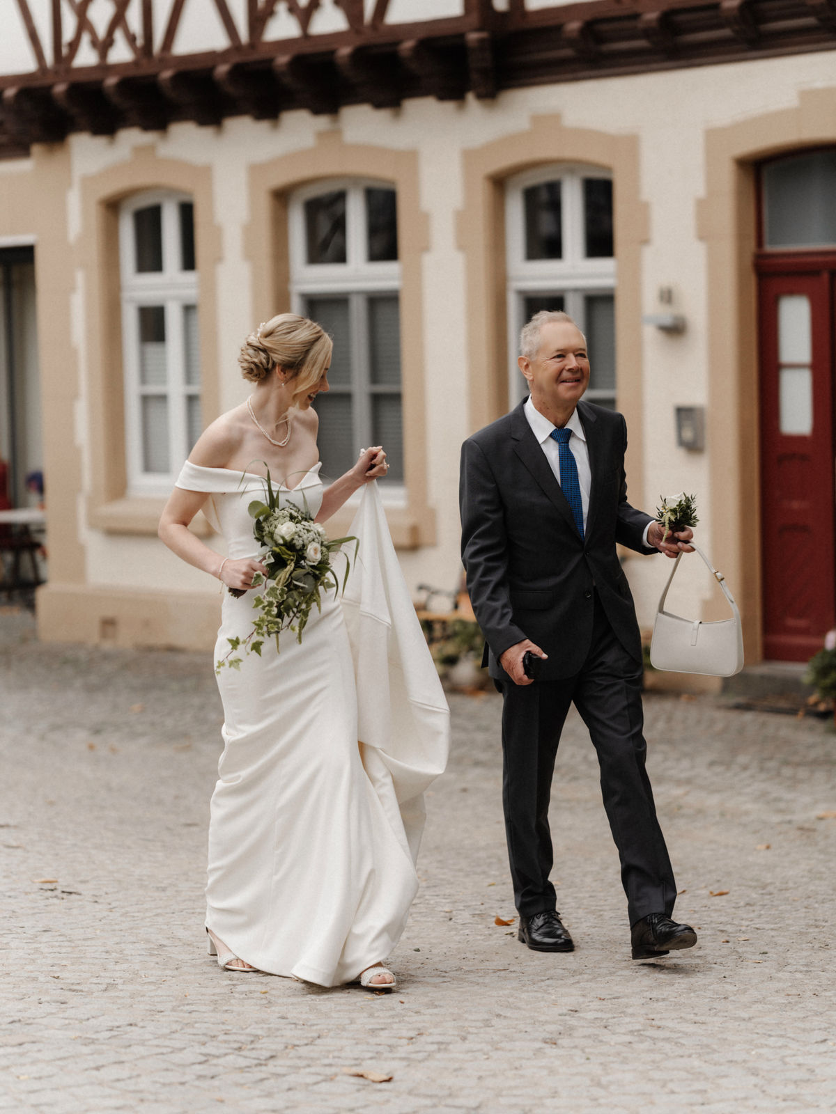 Braut und ihr Vater auf dem Weg zur Trauung im Innenhof von Schloss Eller in Düsseldorf.