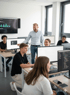 Ein Lehrer zeigt Schülern Code auf einem Computerbildschirm in einem modernen Klassenzimmer.