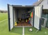 Ein offener grauer Metallcontainer auf einem Fußballfeld, gefüllt mit Trainingsausrüstung wie Hütchen und Westen.