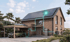 Haus mit Solarpaneelen, Energiemanagement-System, Wärmepumpe und E-Auto am Ladepunkt, verbunden durch leuchtende Linien.