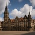 Dresdner Residenzschloss mit hohem Turm, Uhr und braunem Dach unter blauem Himmel mit weißen Wolken.