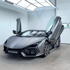 Grauer Lamborghini Sian mit geöffneten Scherentüren in einer Garage.