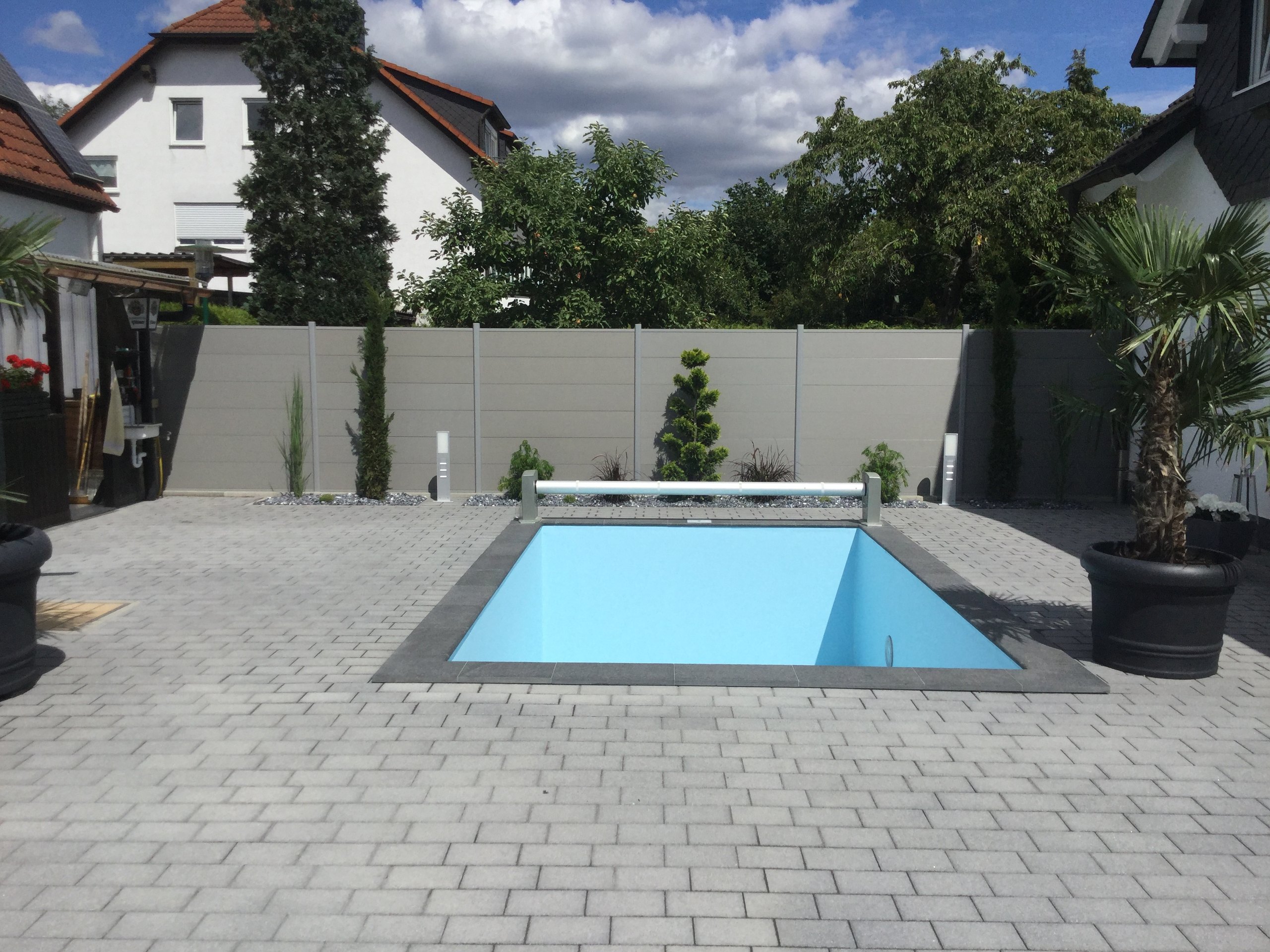 Pool mit Pflasterfläche und Sichtschutzzaun