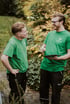 Two smiling men in green "DIAMCLEAN" shirts and black pants talk outdoors, one holding a tablet.