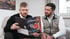 Fabian und Christian Roßmann schauen in den Bauunternehmer-Report auf einer Couch.