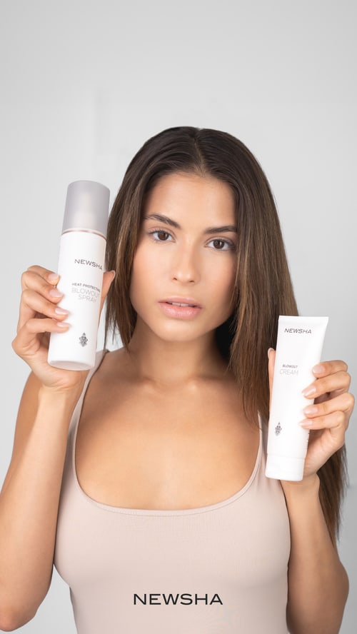 Frau hält Newsha Heat Protection Blowout Spray und Blowout Cream in den Händen.