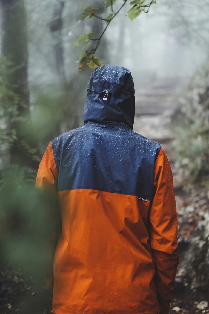 Person in Regenjacke auf einem nebligen Waldweg