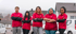 Eine Gruppe von 14 Mitarbeitern in Arbeitskleidung steht lächelnd vor einem Gebäude.